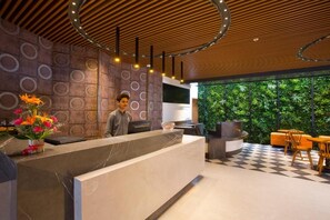 A modern reception area with a marble counter, a TV, and a seating area with a checkered floor. - Fountain Tree by TGI - JP Nagar, Bangalore (Bengaluru)