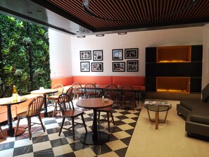 A modern indoor space with a checkered floor, wooden furniture, a green wall with plants, and framed pictures on the wall. - Fountain Tree by TGI - JP Nagar, Bangalore (Bengaluru)