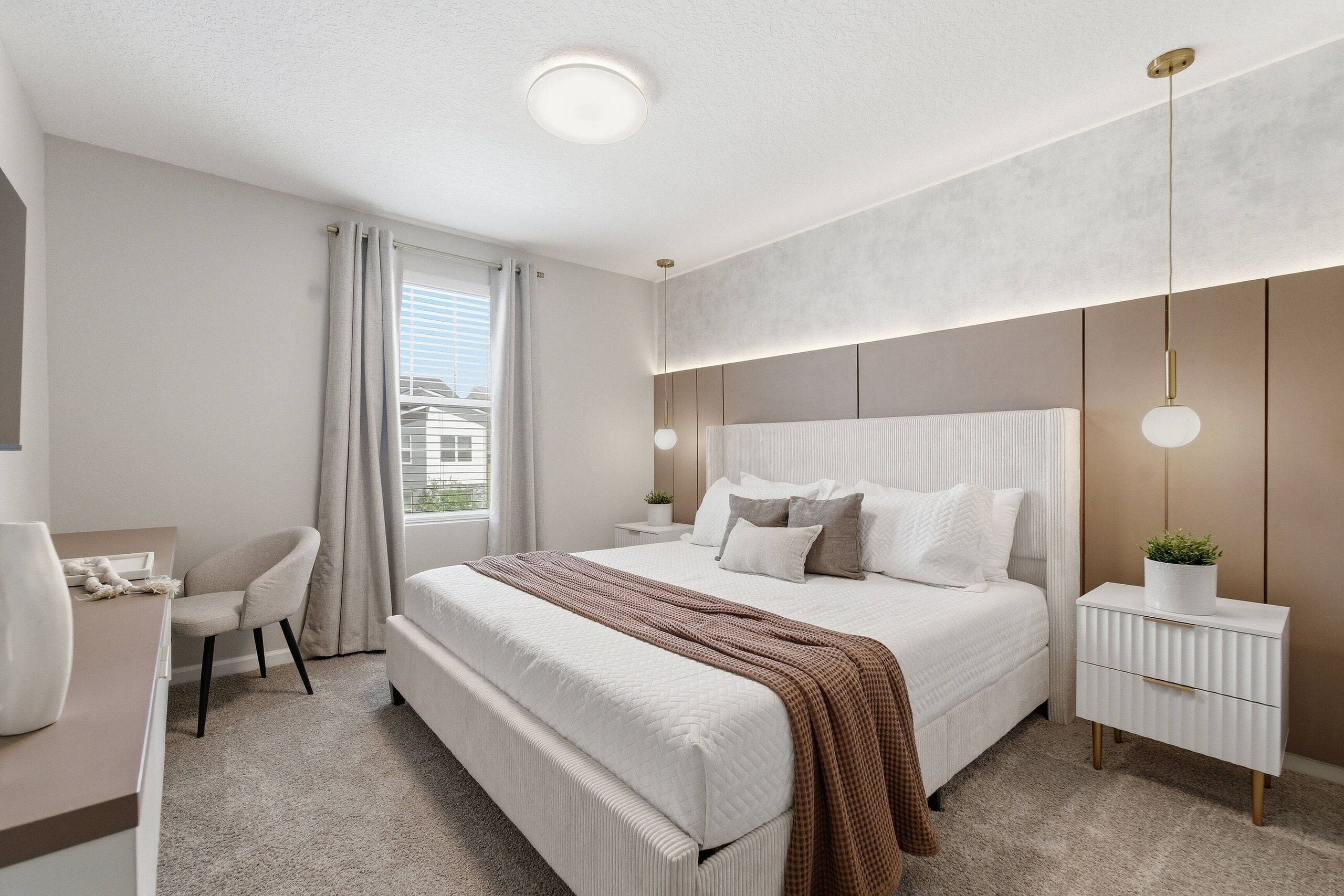 A modern bedroom with a large bed, bedside tables, a desk, and a chair.