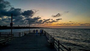 A pier extending into a body of water with a sunset in the background. - Cabaña Olas Del Mar (San Bernardo del Viento)