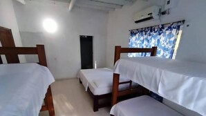 A room with bunk beds, a door, an air conditioning unit, and a window with curtains. - Cabaña Olas Del Mar (San Bernardo del Viento)