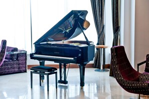 A grand piano in a well-lit room with a modern chair and a small table.