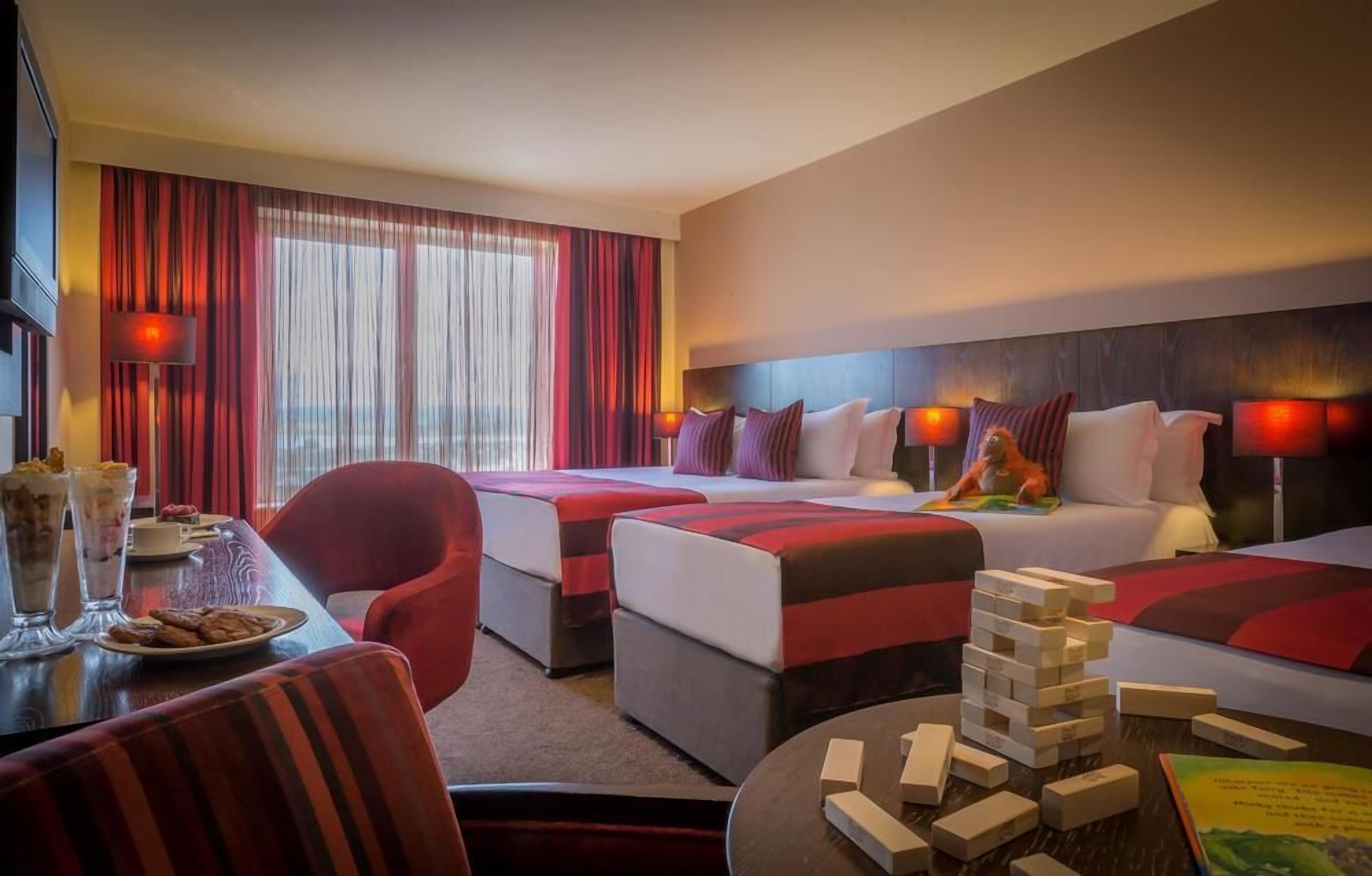A hotel room with two beds, a dining table with food, and a jigsaw puzzle.