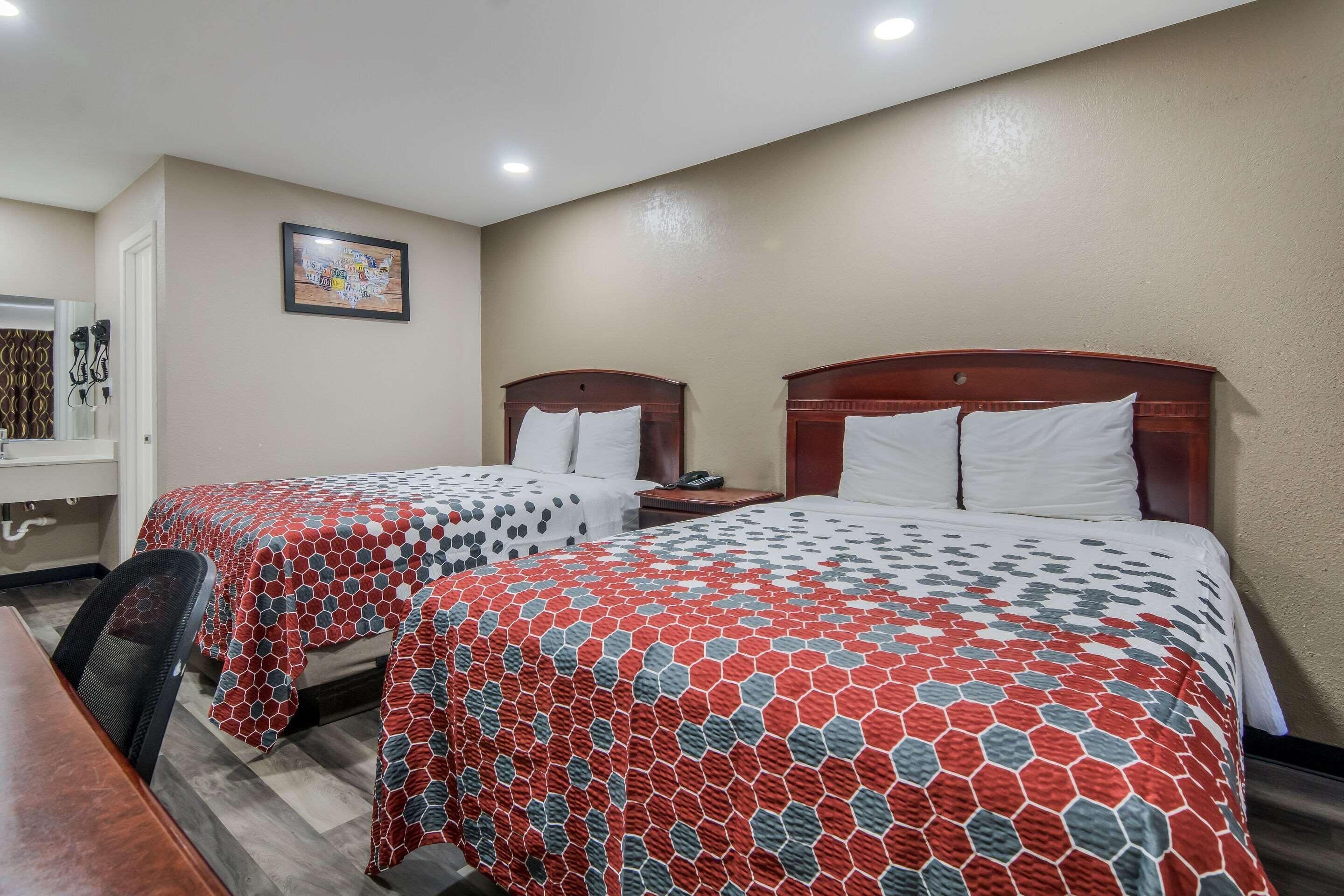 A hotel room with two beds, a desk, and a chair.