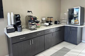 Eine Küchenzeile mit einer Kaffeemaschine, einem Kühlschrank und einem Getränkeautomaten.