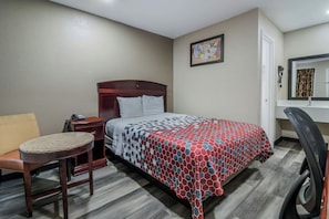 A hotel room with a bed, a round table, a chair, a nightstand, a desk, and a mirror. - Super 8 by Wyndham Waco North I-35 (Waco)