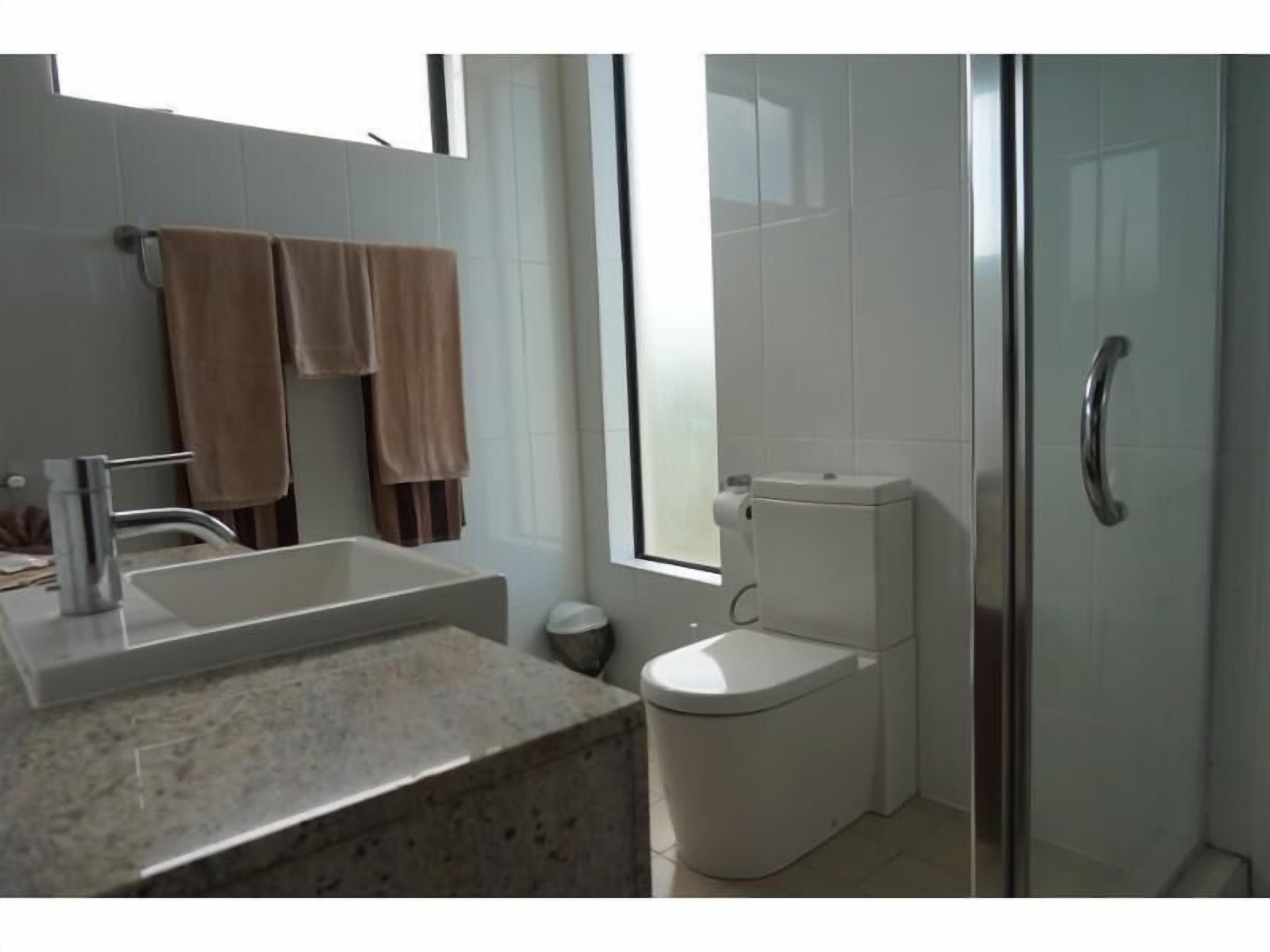 A bathroom with a sink, toilet, and shower area.