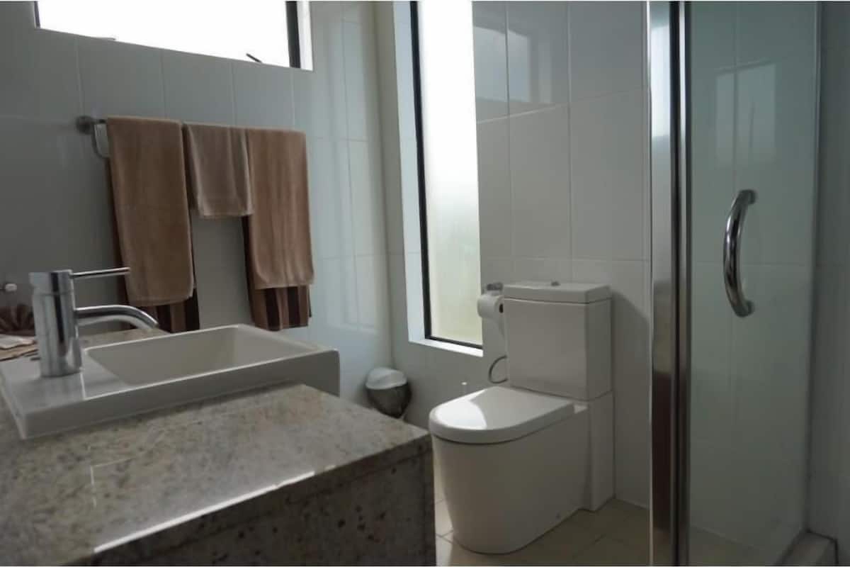 A bathroom with a sink, toilet, and shower area.