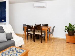 A modern living room with a sofa, a dining table with chairs, a coffee table, and a potted plant. - Apartment next to the Beach in Roses, Costa Brava! 2 Bedrooms, Sea Views, Free Wi-Fi. Book now! (Roses)