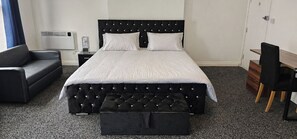 Une chambre à coucher avec un lit, un canapé, un bureau et une chaise.