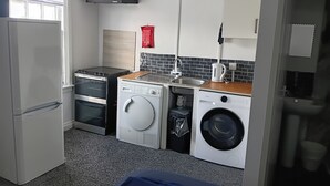 Kompakti keittiö, jossa on jääkaappi, uuni, pesukone ja pesuallas.