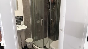 Une salle de bain avec une douche à parois de verre, un lavabo et des toilettes.