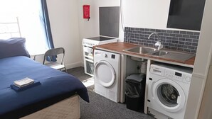 Une chambre d’hôtel équipée d’un lit, d’une machine à laver, d’un sèche-linge, d’un lavabo et d’une télévision.