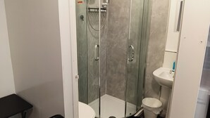 A bathroom with a glass-enclosed shower, a white toilet, and a sink. - Studio Sleeps 2 with Parking (Oldbury)