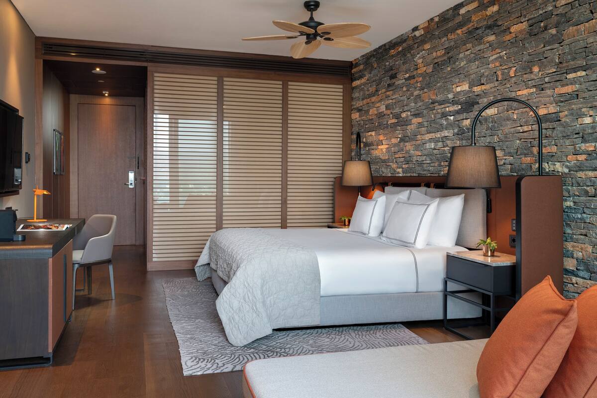 A modern hotel room with a large bed, a desk, and a TV.