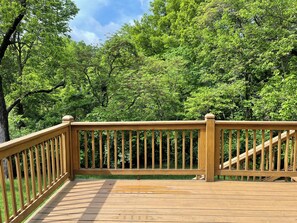 Eine Holzterrasse mit Geländer, umgeben von dichtem Grün.