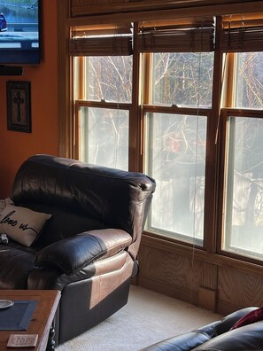 Ein Wohnzimmer mit einer Ledersofa, einem Couchtisch und einem an der Wand befestigten Fernseher.