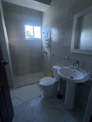 Een douche, handdoeken, zeep, toiletpapier