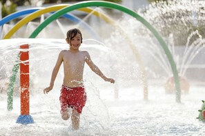A child playing in a water feature with colorful arches. - Ikos Aria (Kos)