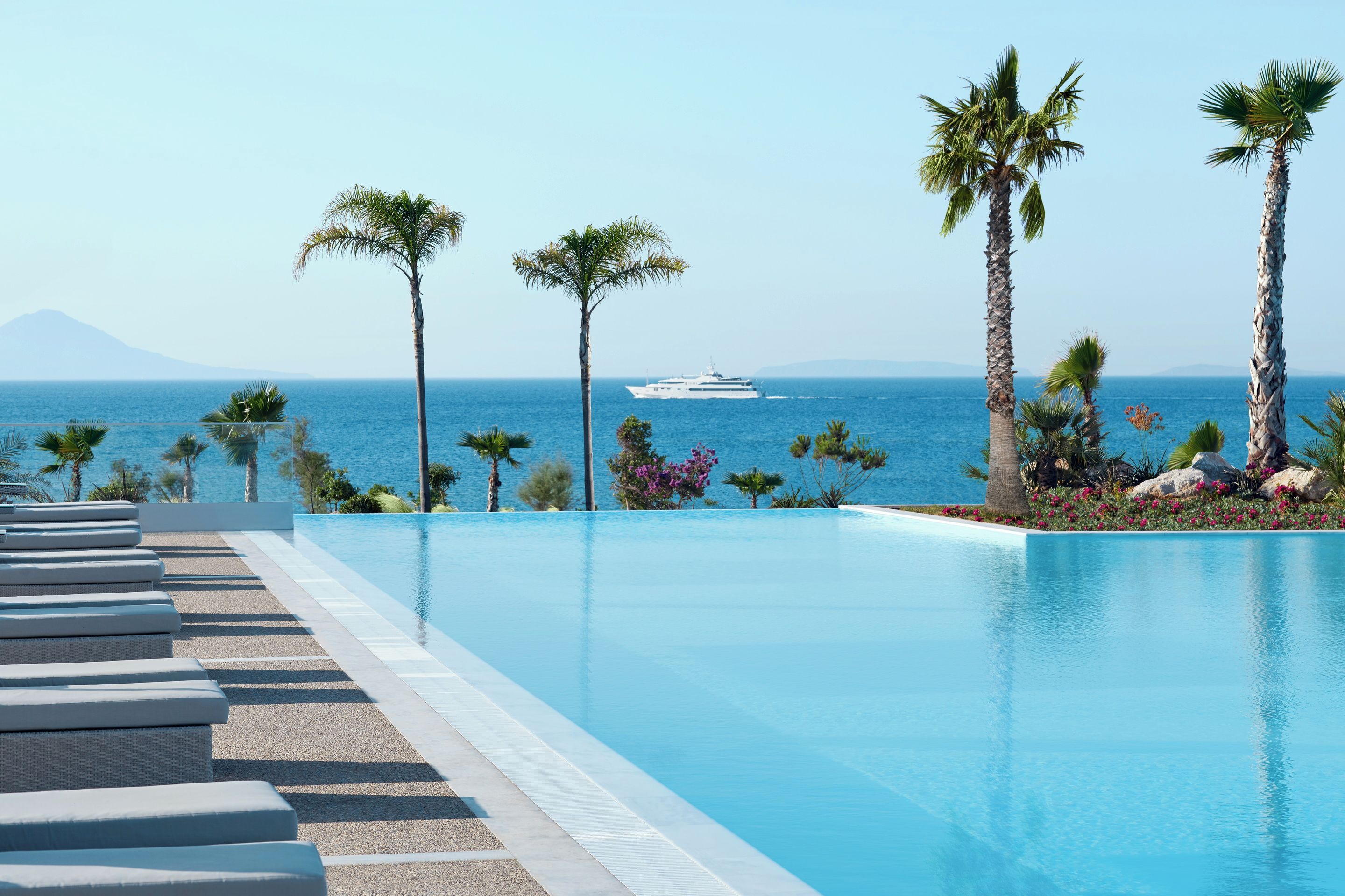 Una piscina con vista sul mare e uno yacht all'orizzonte.