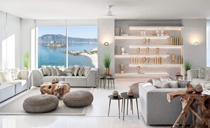 Una sala de estar moderna con un amplio ventanal que ofrece vistas al mar, que incluye sofás, otomanas y una mesa de centro de madera.