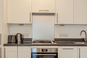 Eine Küche mit weißen Schränken, einem Gasherd, einem Toaster und einem Backofen.