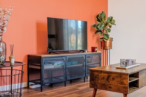 Ein modernes Wohnzimmer mit einem großen Flachbildfernseher, einem Holztisch, einem Metallschrank und einem Blumentopf.