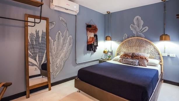 Un dormitorio con una cama, una silla colgante y un aire acondicionado instalado en la pared.
