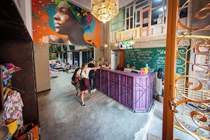 Una zona de bar con una barra púrpura, un mural en la pared y una pizarra con escritura.