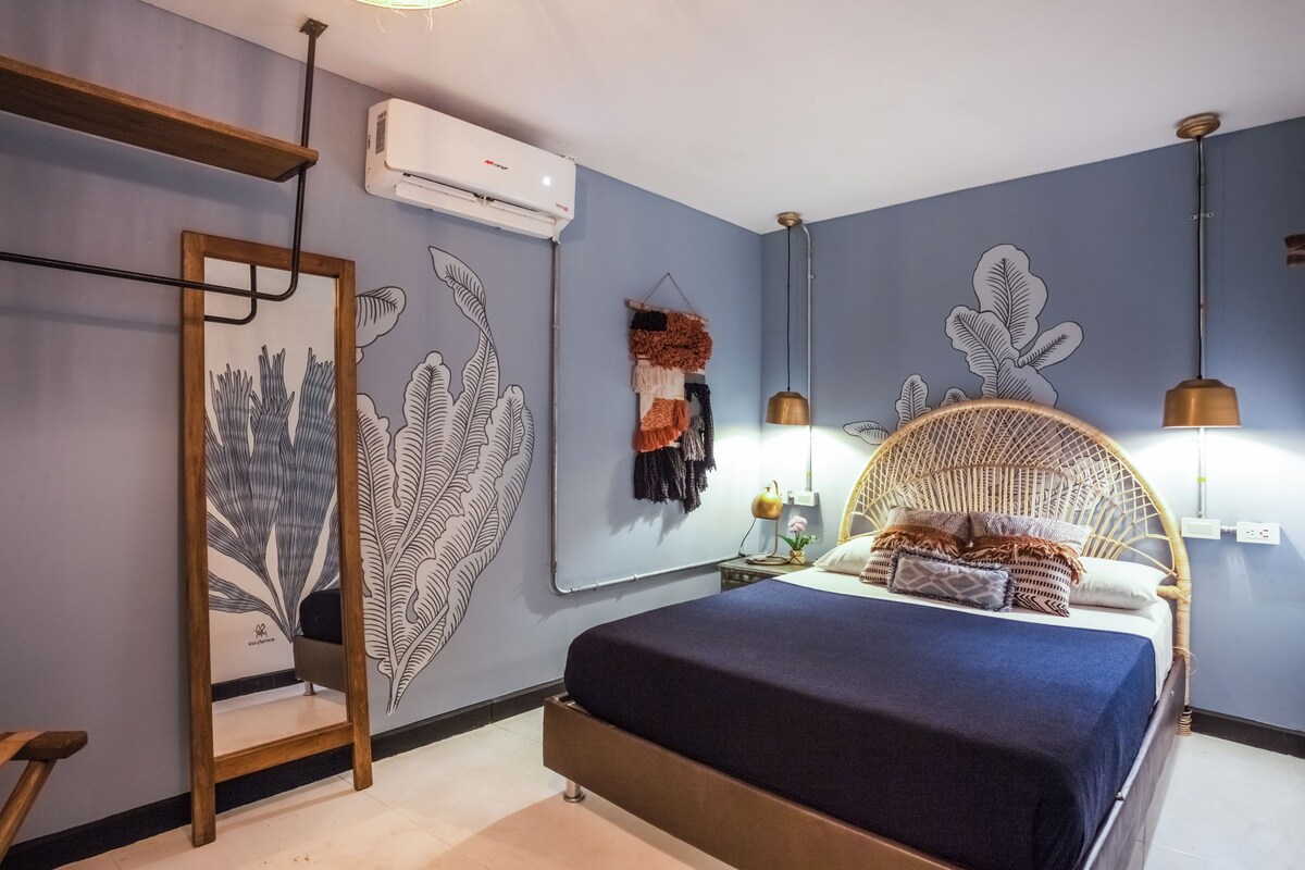 A bedroom with a bed, a hanging chair, and a wall-mounted air conditioner.