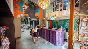 Una zona de bar con una barra púrpura, un mural en la pared y una pizarra con escritura.