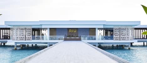 Un hotel sobre el agua con un largo paseo que lleva a un edificio con el rótulo 'RIU'.