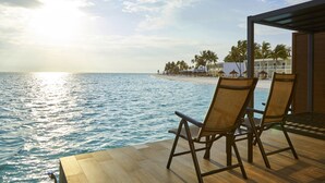 A deck with two chairs overlooking a beach and ocean.