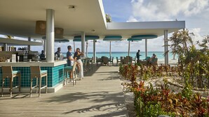 A resort bar with outdoor seating and a view of the ocean.