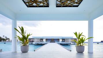Uma galeria coberta que leva a um edifício com a placa "RIU", em frente a uma piscina.