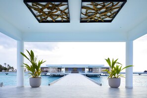 A covered walkway leading to a building with the sign "RIU" in front of a pool. - Hotel Riu Atoll (Kedhigandu)