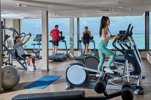 A gym with cardio machines, weight equipment, and a large exercise ball.