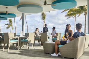 Un salón junto a la playa con mobiliario de mimbre y vistas al océano.
