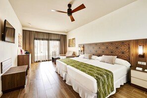 A hotel room with a large bed, a desk, a chair, a TV, and a ceiling fan. - Hotel Riu Atoll (Kedhigandu)