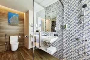 A modern bathroom with a glass shower enclosure, a white sink, and a wooden vanity.