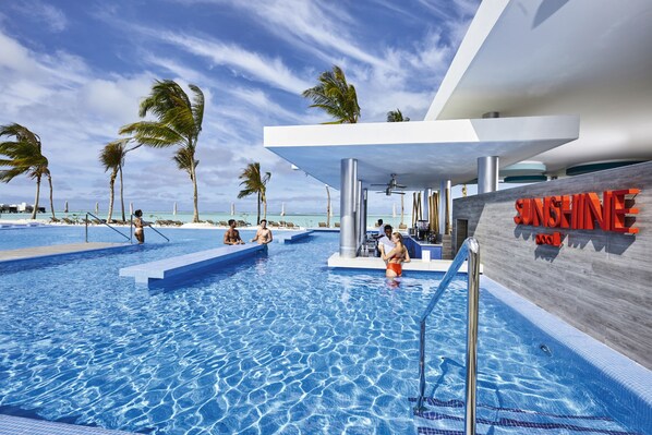 A swimming pool area with clear blue water, palm trees, and a modern building with a sign that reads 'SINGHINE.'
