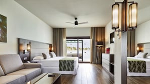 A hotel room with two beds, a sofa, a coffee table, and a ceiling fan.