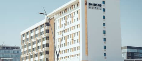 Un hotel de varios pisos con un letrero llamativo que dice 'ONOMA HOTEL' en la fachada.