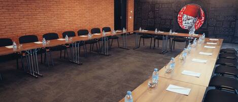 A conference room with a long table, chairs, water bottles, and a brick wall.
