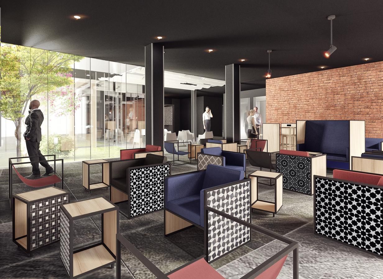 Un área de lounge moderna con disposición de asientos, pared de ladrillo y ventanas amplias.