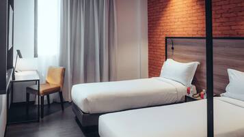 Ein Hotelzimmer mit zwei Betten, einem Schreibtisch, einem Stuhl und einer Ziegelwand.