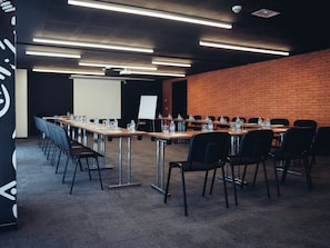 A conference room with long tables, chairs, water bottles, and a projector screen. - Onomo Sidi Maarouf (Casablanca)