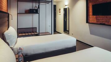 Una habitación de hotel con dos camas, un televisor montado en la pared y un minibar.