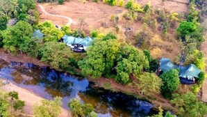 An aerial view of a campsite with tents, a river, and surrounding greenery. - Banjaar Tola A Taj Safari Kanha National Park (Bichhiya)