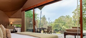 A tent-style room with a bed, a table, and chairs, and a view of the outdoors. - Banjaar Tola A Taj Safari Kanha National Park (Bichhiya)